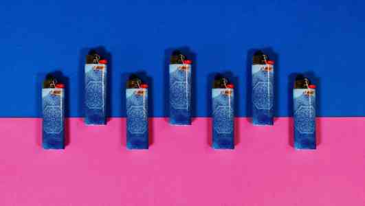 Seven blue Bic lighters arranged in a crenellated pattern on a blue and pink background.