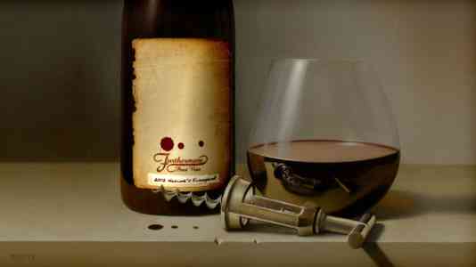 Close-up of a glass of red wine next to a Furthermore bottle and a silver corkscrew.